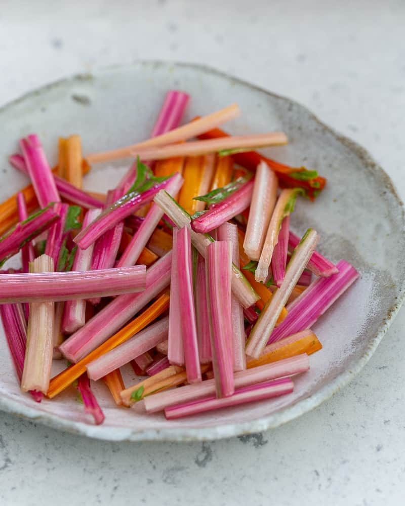 A plate with cut stems of the swiss chard ready to be blanched