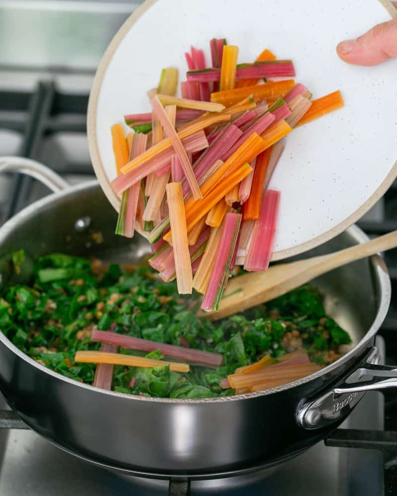 Adding blanched swiss chard stems to lentils to make Chopped garlic added to brown lentils in pan to make Baked sweet Potato with Lentils and Swiss Chard