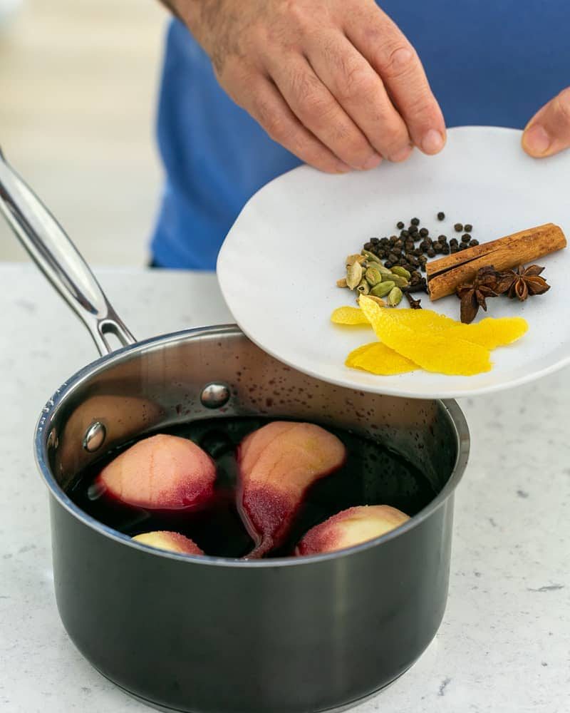 Add whole spices to the pears in wine