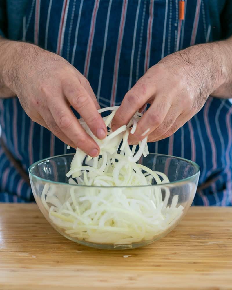 Sliced brown onion in bowl to make topping for baked sweet Potato with Lentils and Swiss Chard