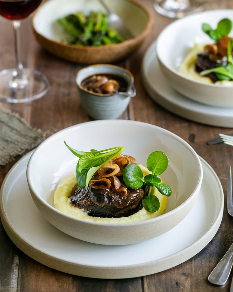 Beef cheeks served with mashed potatoes and shallot jus in a wide bowl