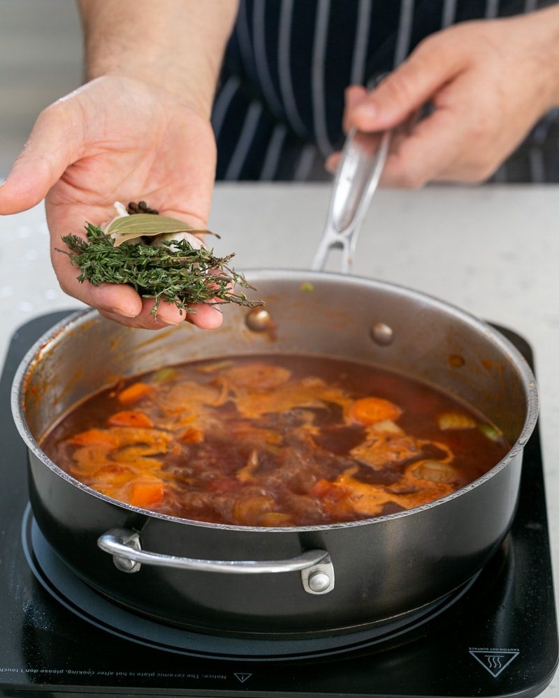 Adding whole spices to cooking jus in pan