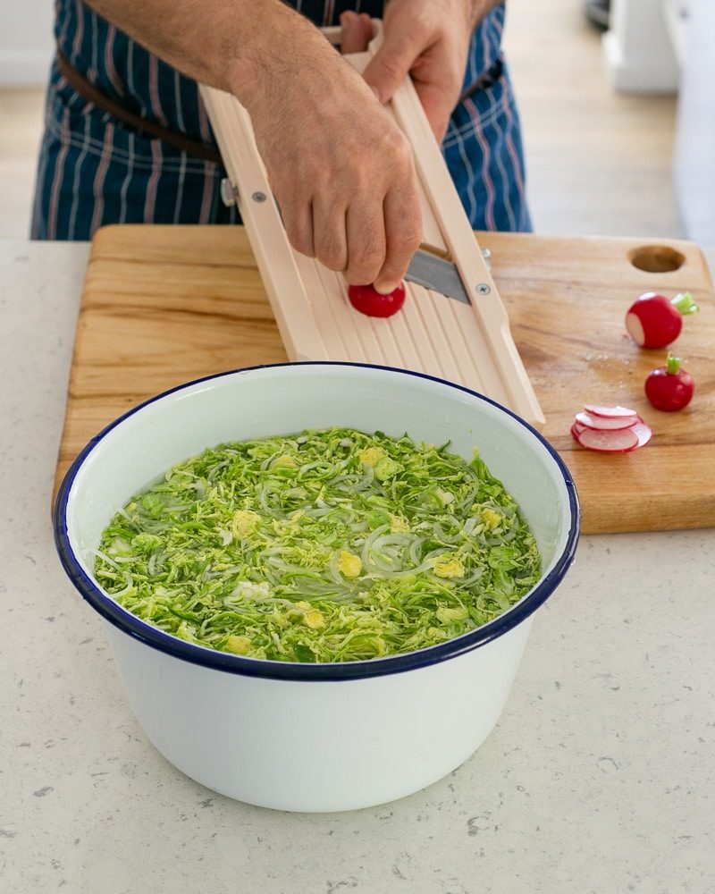 Shaved brussels sprouts in cold water bath to keep crisp