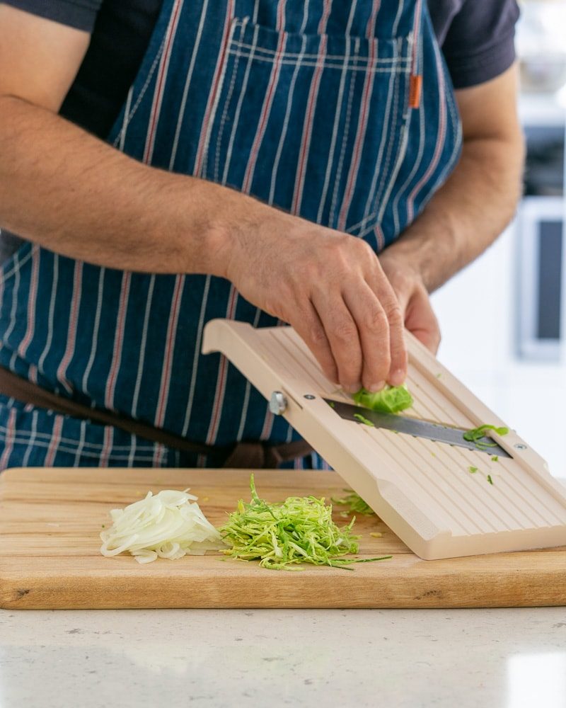 Shaving brussels sprout on a Japanese mandoline