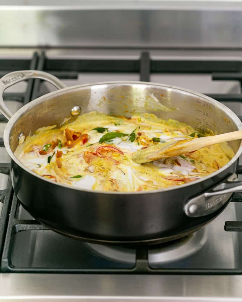 Coconut cream and water added to the curry sauce mix cooking cooking in the pan