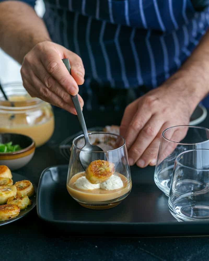 Adding caramelized banana slices on top of dulche de leche in glass