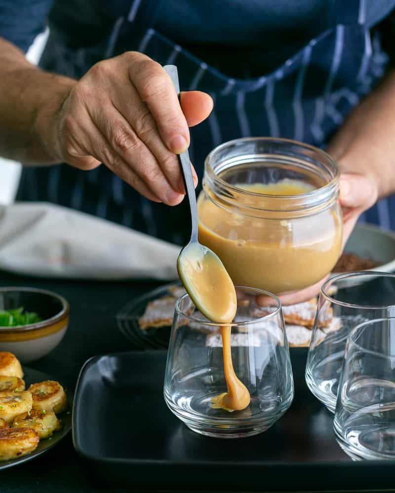 Adding a spoonful of the Dulche de leche at the bottom in the glass to assemble Dulce de Leche Verrine with Banana and whipped Cream