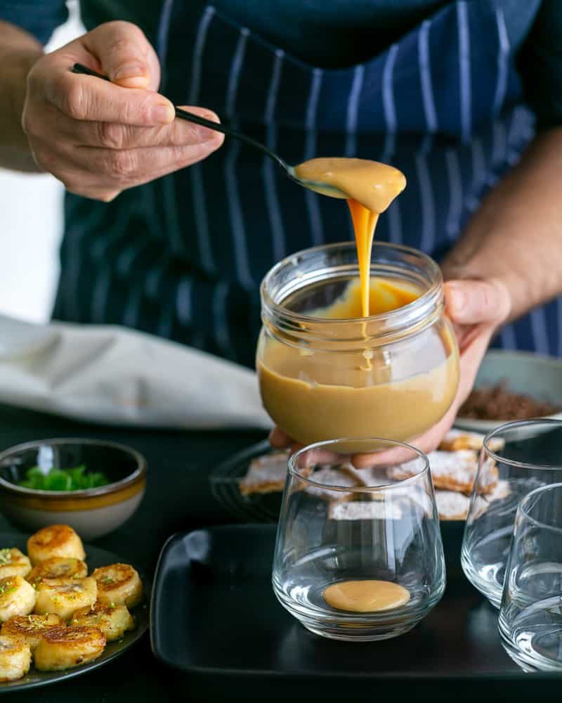 Adding a spoonful of the Dulche de leche at the bottom in the glass to assemble Dulce de Leche Verrine with Banana and whipped Cream