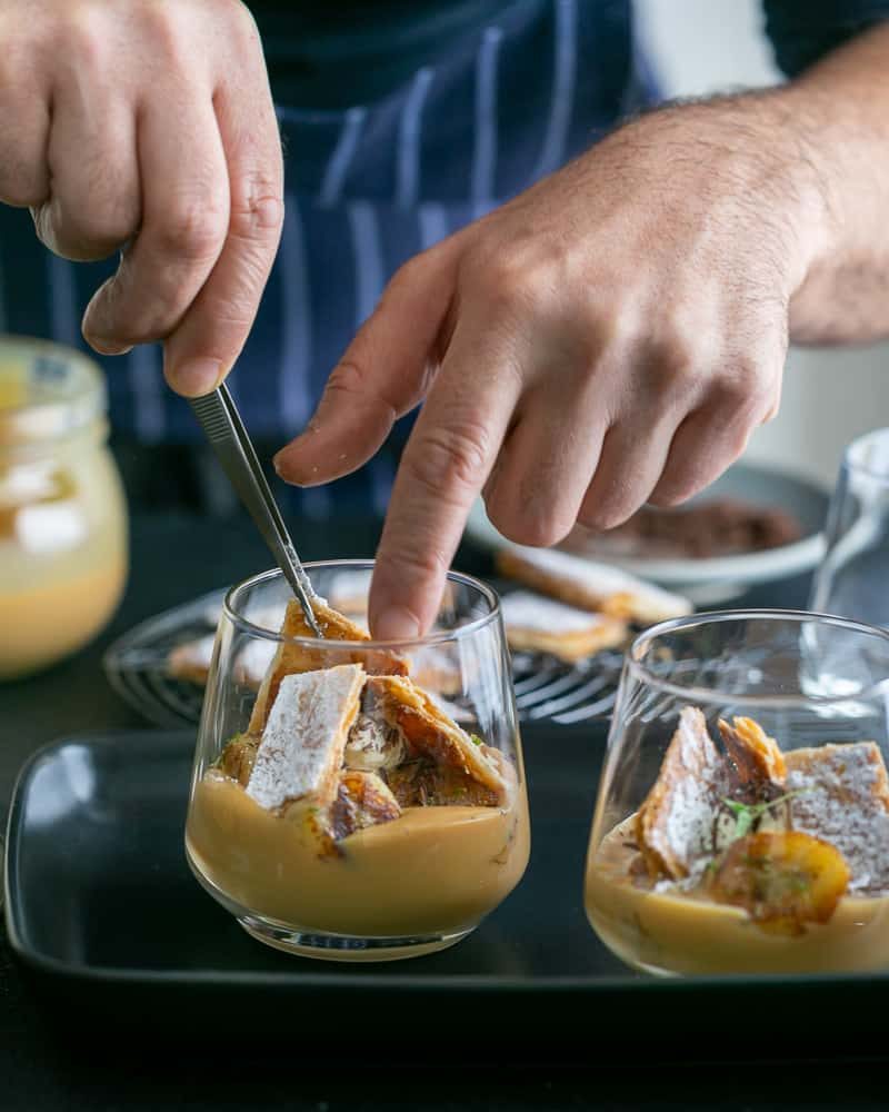 Adding puff pastry chard to assemble Dulce de Leche Verrine with Banana and whipped Cream