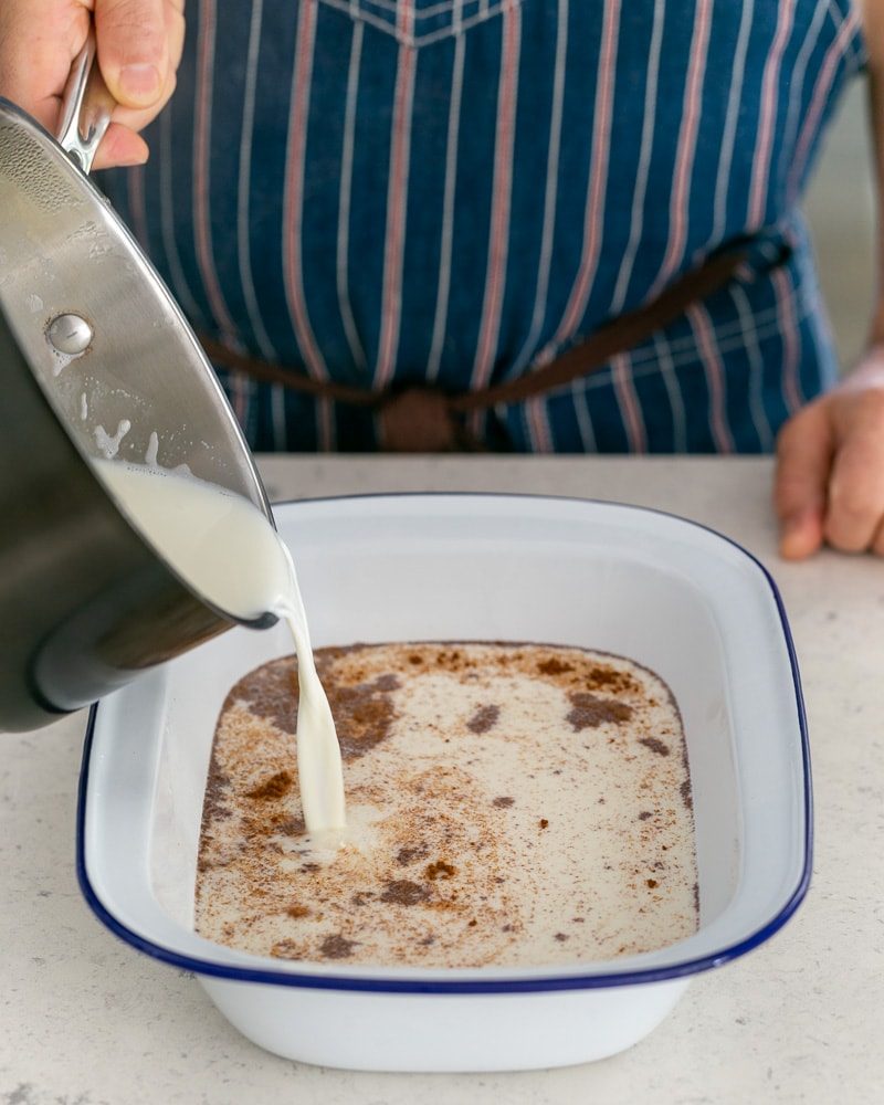 Warm milk added to rice, cinnamon and sugar in baking dish