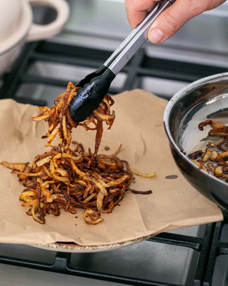 Fried onions to be used as topping for Chopped garlic added to brown lentils in pan to make Baked sweet Potato with Lentils and Swiss Chard