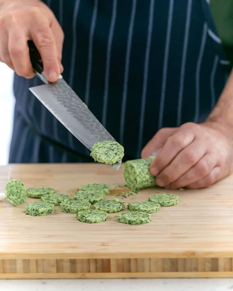 Slicing garlic butter in round discs for scallops baked in the shell