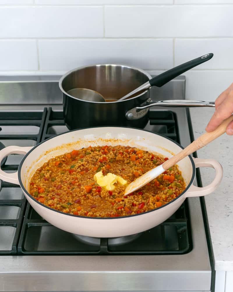 Adding butter to finish cooking fregola sarda with prawn stock