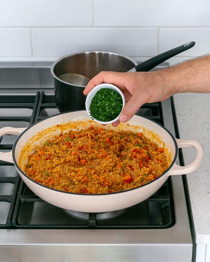 Adding parsley to finish cooking fregola sarda with prawn stock