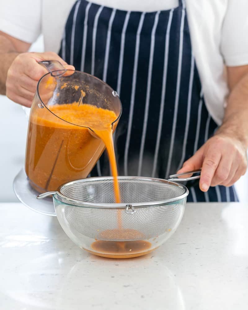 Blended prawn stock poured through a sieve into a bowl