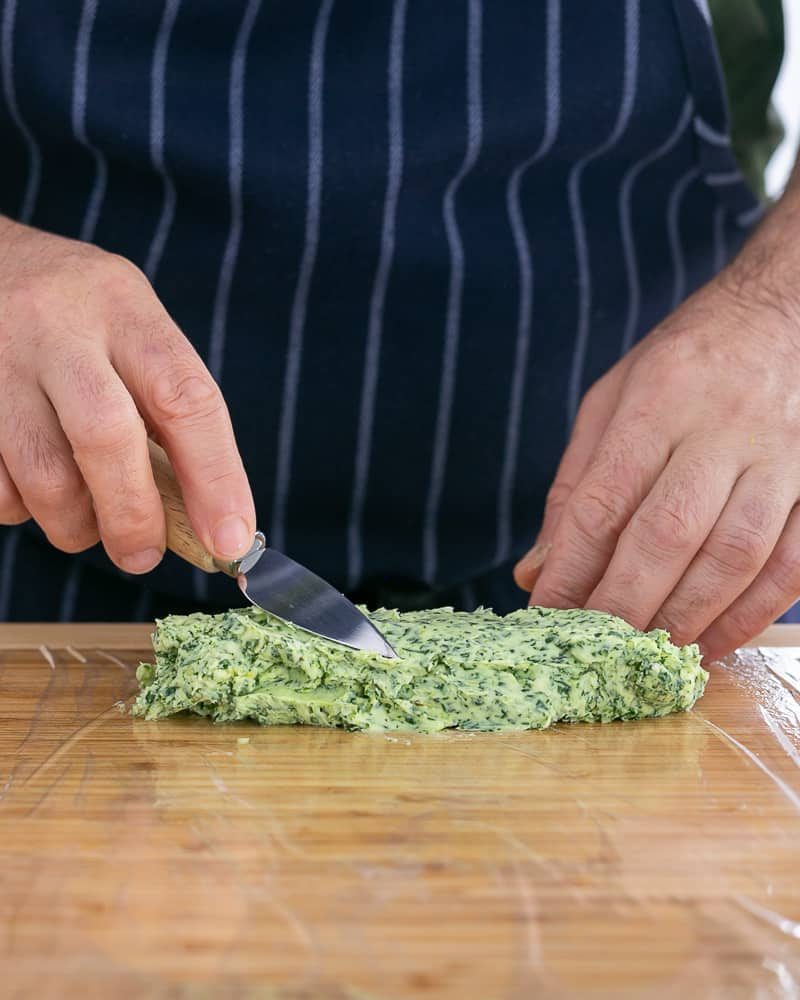 Soft garlic herb butter transferred to cling film to roll into a butter log