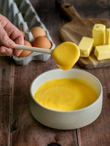 Hollandaise sauce dripping of a spoon into a bowl