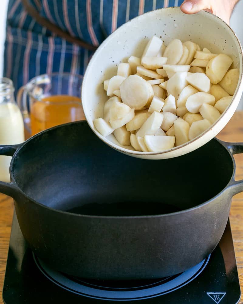 Adding sliced sunchokes into a hot pot for jerusalem artichoke soup