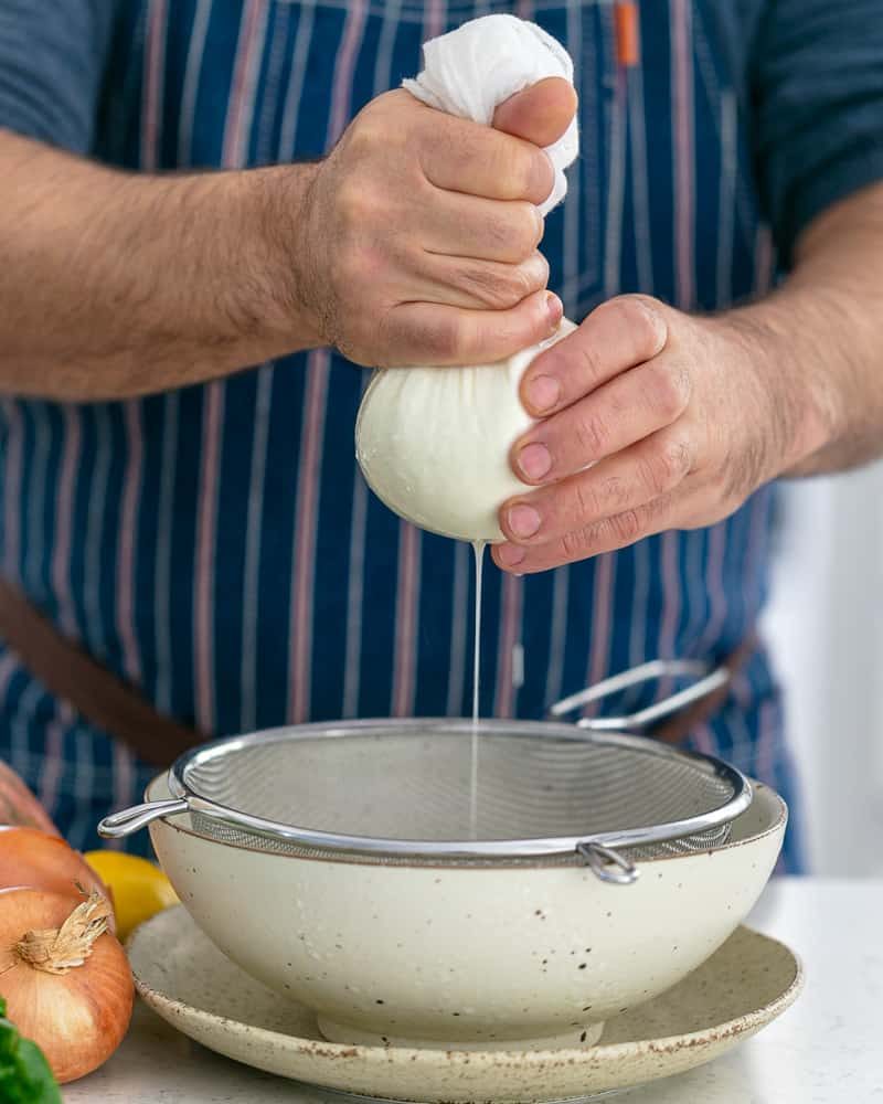 A person making labneh by squeezing out the whey from the yoghurt