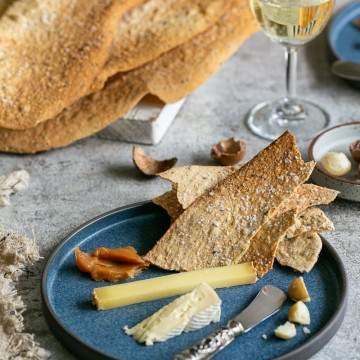Spiced lavosh crackers served in a plate with cheese and wine