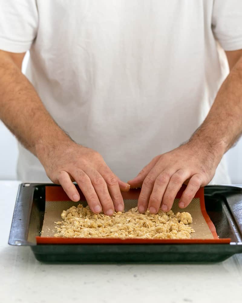 Person spreading the pat crumble on a baking tray