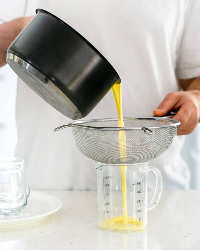 Straining the cooled cream mix through a sieve into a jug