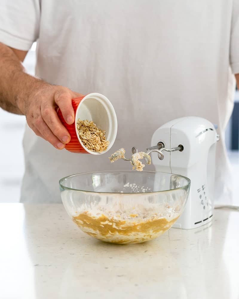 Person adding oats to the flour sugar butter mix to make crumble