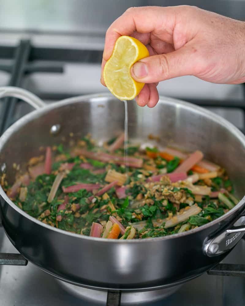 Squeeze of lemon added to lentis and swiss chard in pan to make Chopped garlic added to brown lentils in pan to make Baked sweet Potato with Lentils and Swiss Chard