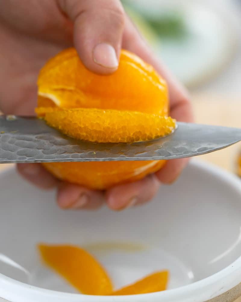 cutting an orange segment with a sharp knife