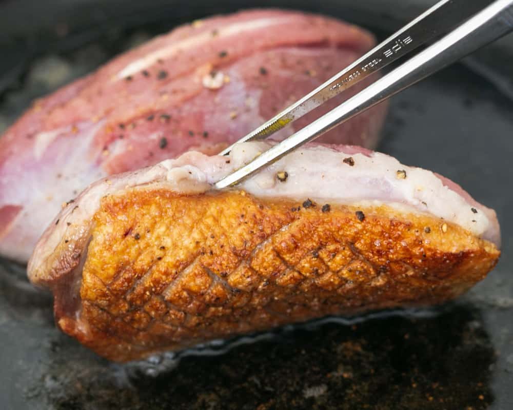 Pan frying duck breast skin down in a hot iron skillet