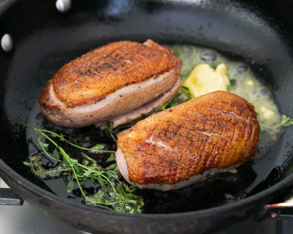 Pan fried duck breasts in an iron skillet with butter and thyme