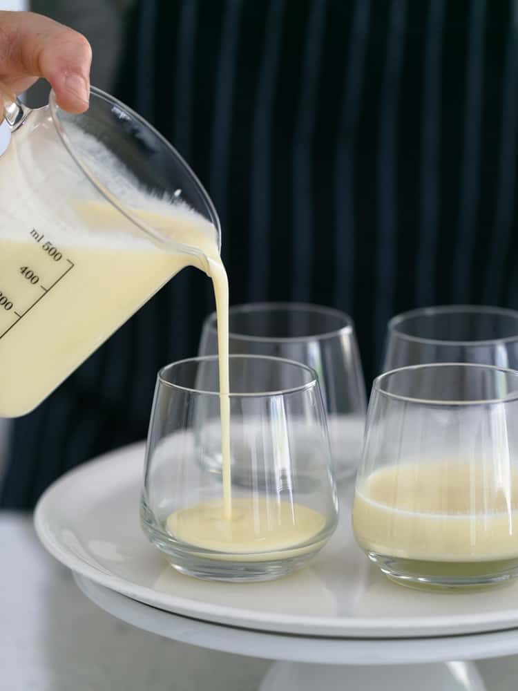 Panna cotta mix being poured into dessert glasses to set