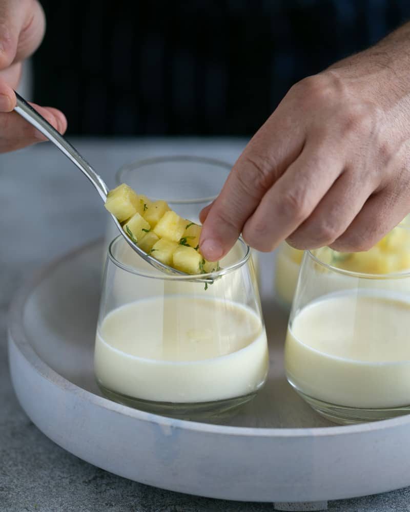 Adding pineapple on top of set panna cotta in a desert glass