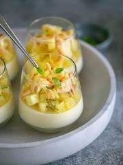 Pina Colada Panna cotta topped with pineapple dices, mint leaves and toasted coconut flakes in a dessert glass