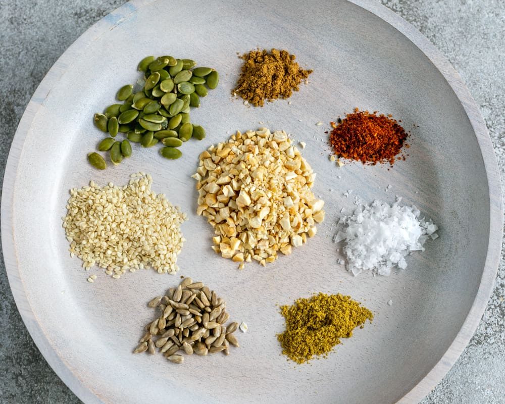 Dukkah ingredients in a round white wooden plate