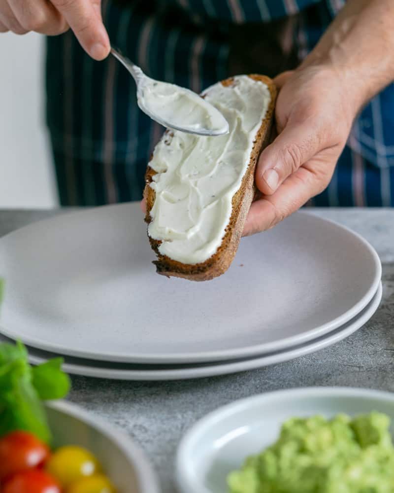 Spreading ricotta cheese on a slice of toasted sourdough