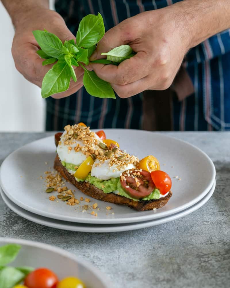 Adding fresh basil leaves on top of dukkah