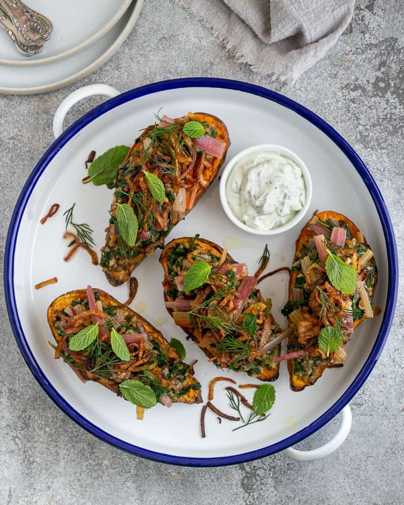 Baked sweet Potato with Lentils and Swiss Chard served in blue and white round enamel bowl with labneh in a small bowl