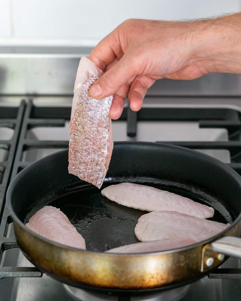 Red snapper fillet added to hot pan for searing