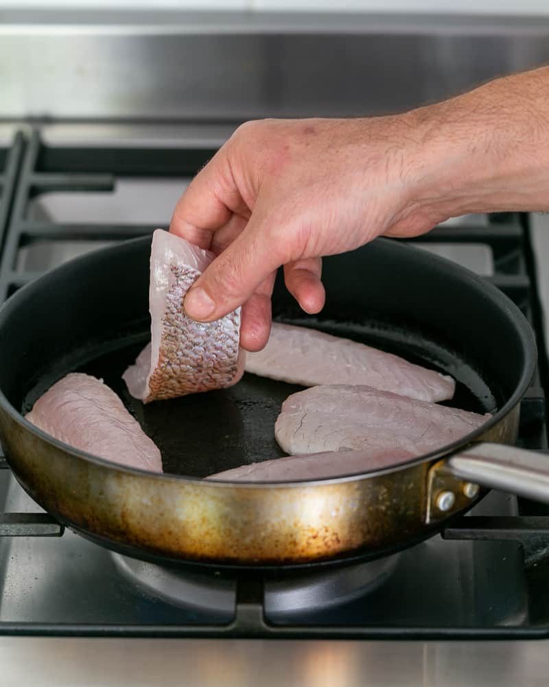 Red snapper fillet added to hot pan for searing