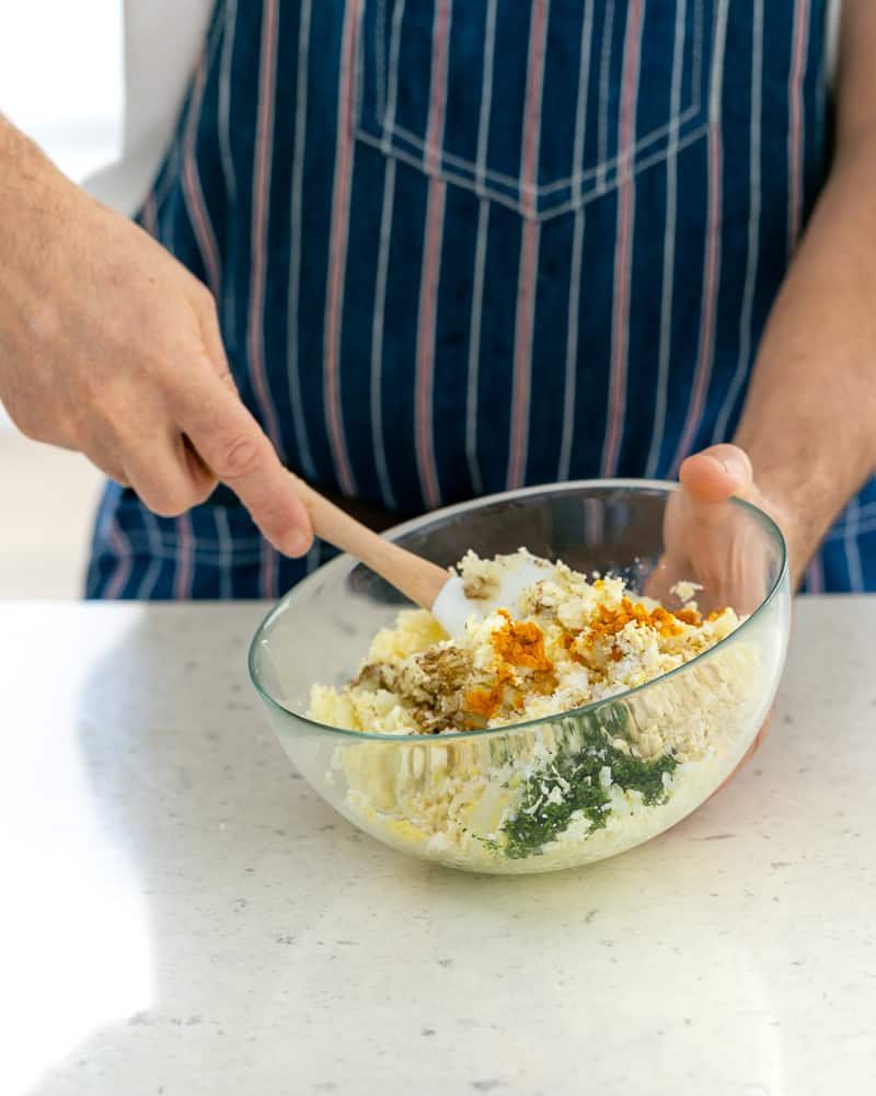 Mixing paneer and potato dumpling ingredients with a spatula