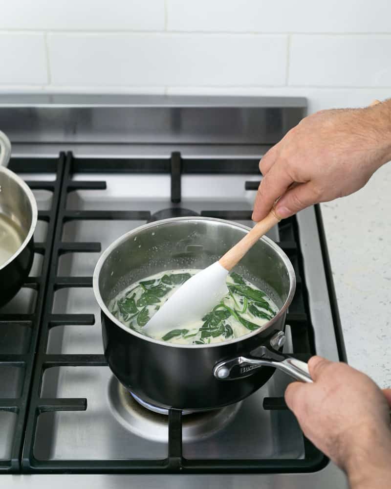 Fresh spinach cooking in vegetable cream stock for the spinach sauce