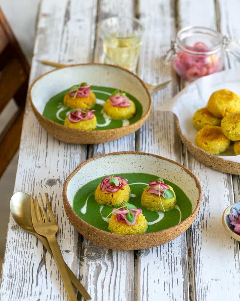 Paneer and Potato Dumplings with Spinach sauce served on a white wooden table