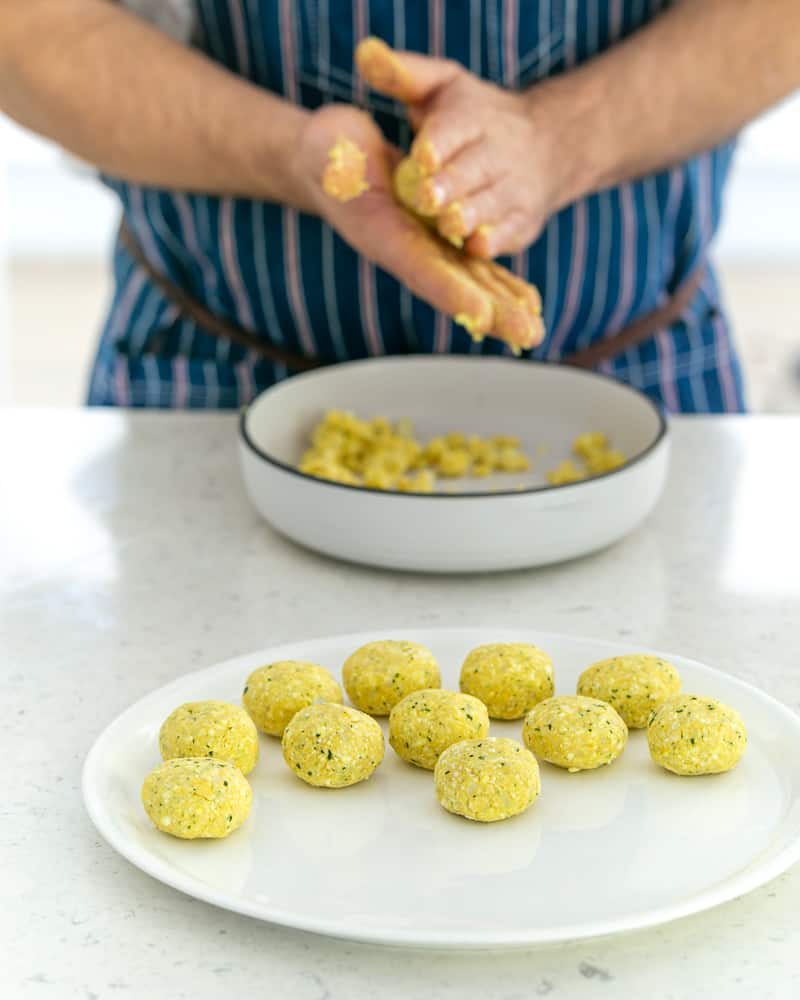 A person rolling balls with the paneer and potato mix