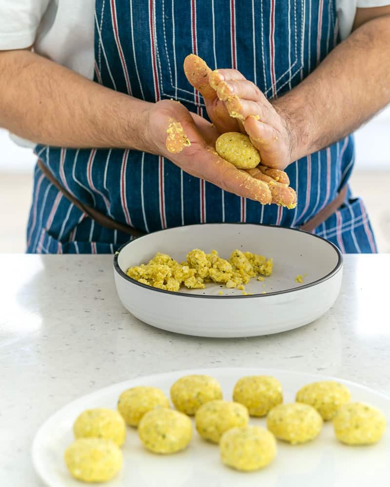 A person rolling balls with the paneer and potato mix