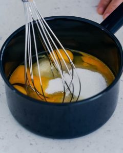 pot with eggs, sugar and whisk