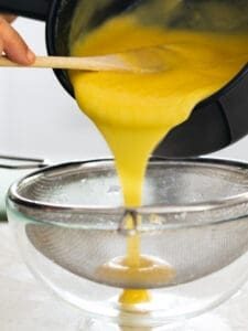 Straining the cooked passionfruit curd through a sieve