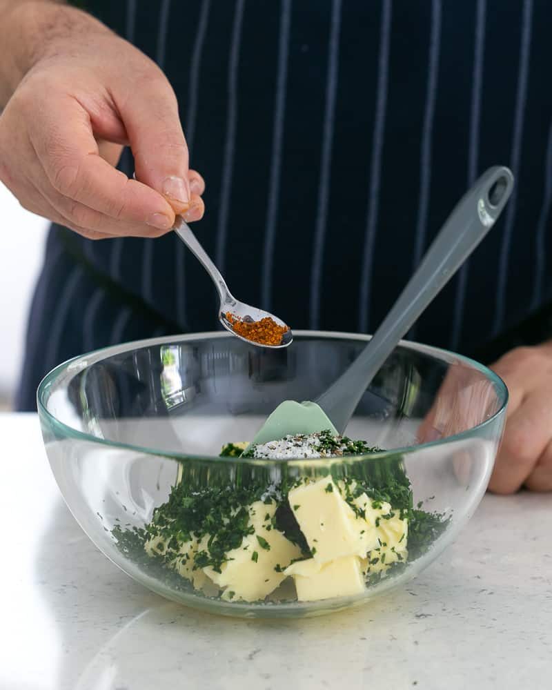 Person adding cayenne pepper to butter to make garlic Herb butter