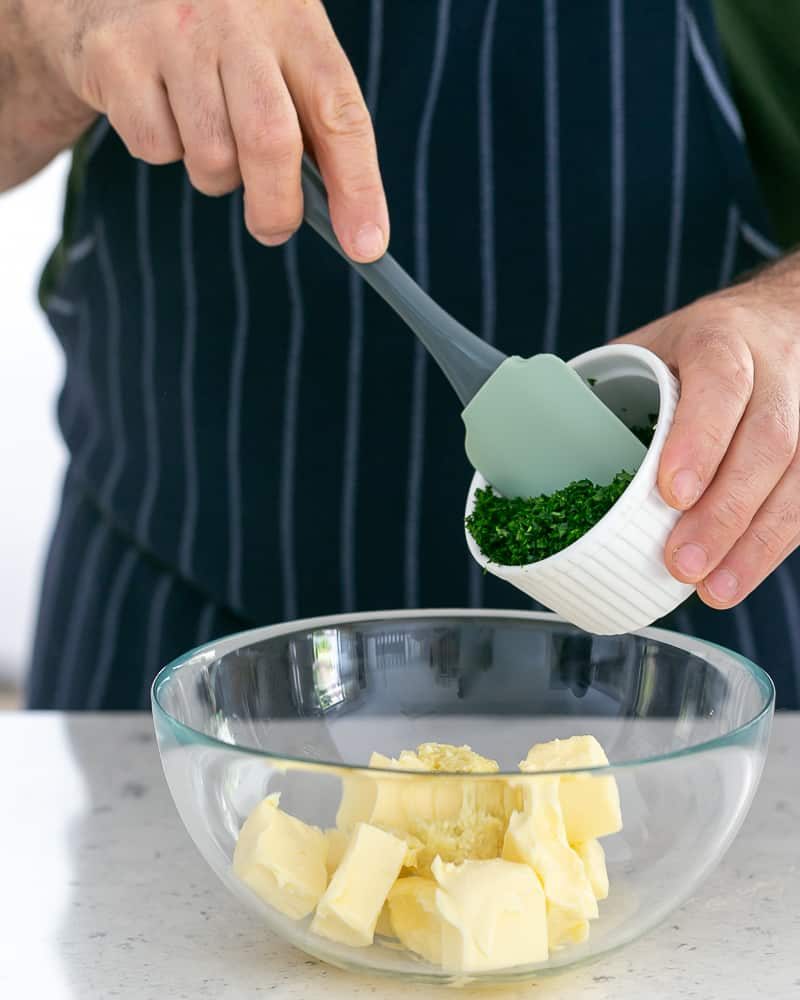Person adding chopped Herb to butter to make garlic parsley butter