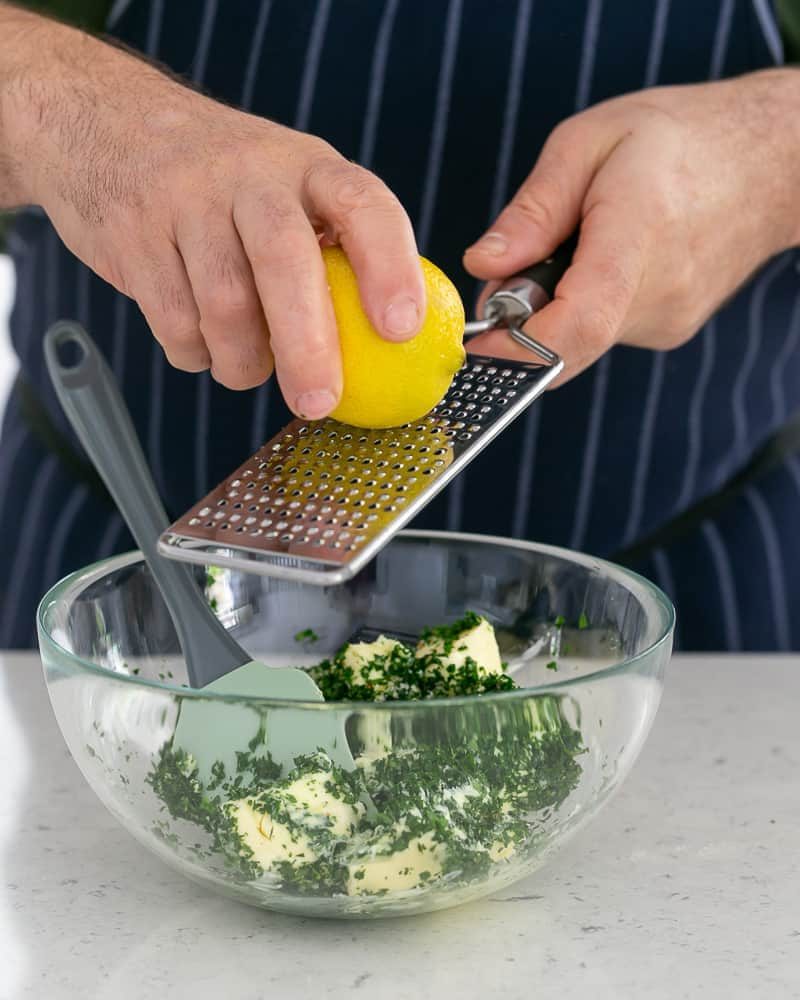 Person lemon zest over butter to make garlic Herb butter